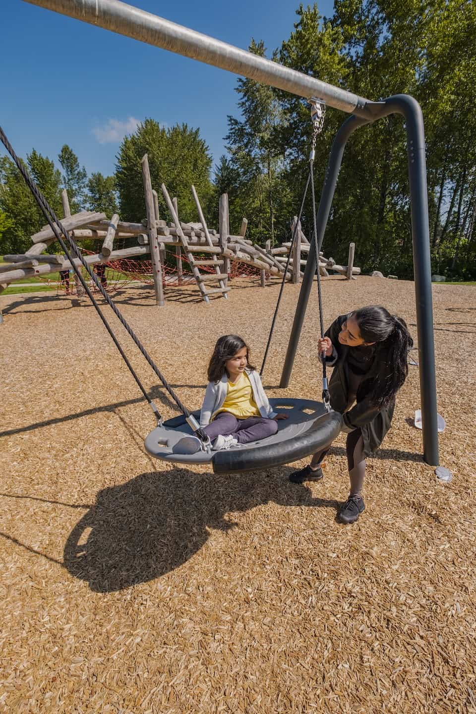 a woman with a child at a swing set on a playground